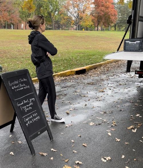 A female student sets up a sandwich board on a fall day.