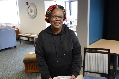 A woman in a black sweatshirt holds Kitchen Coalition meals