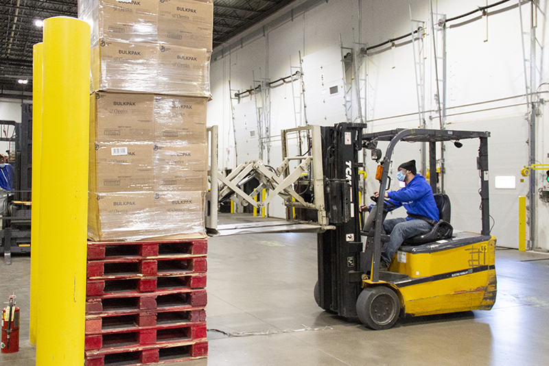 Staff using forklift to lift stack of boxes