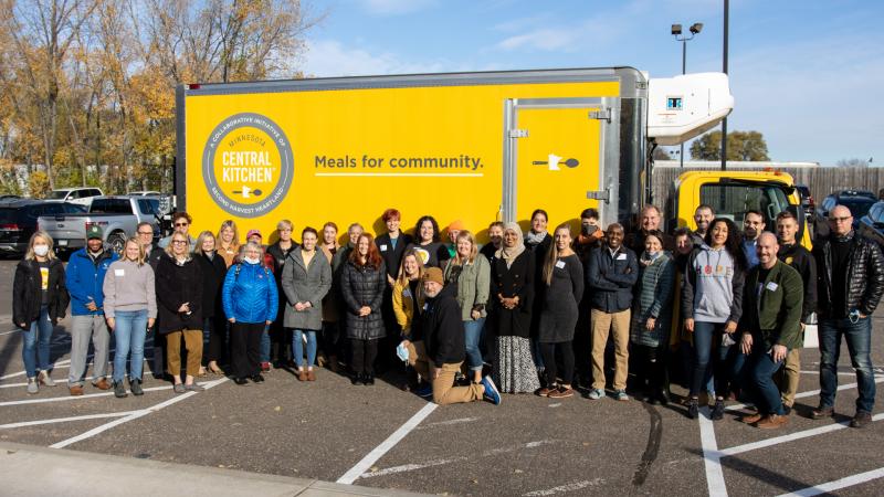 A group of people pose in front of a yellow MCK truck