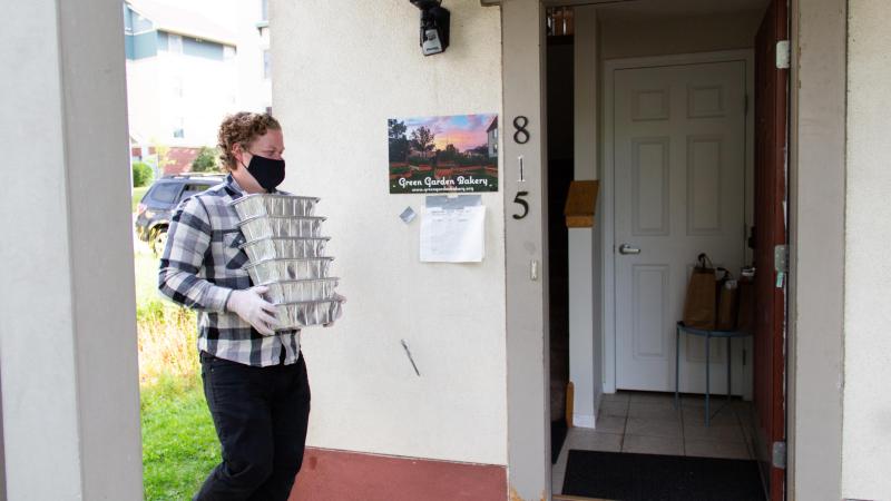 A man carries trays of meals to a neighborhood drop off point