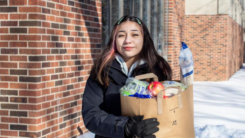 Young woman holds grocery bag outside in winter