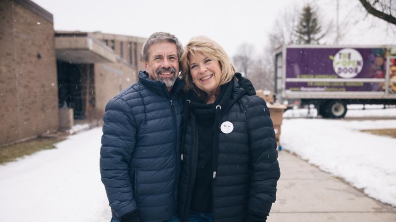 An older couple volunteers outside at winter food distribution
