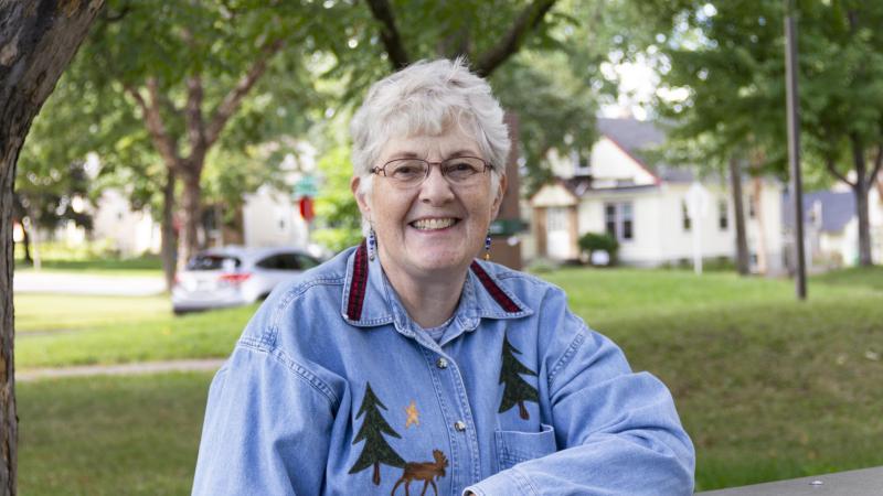 Older woman sitting at picnic table smiling