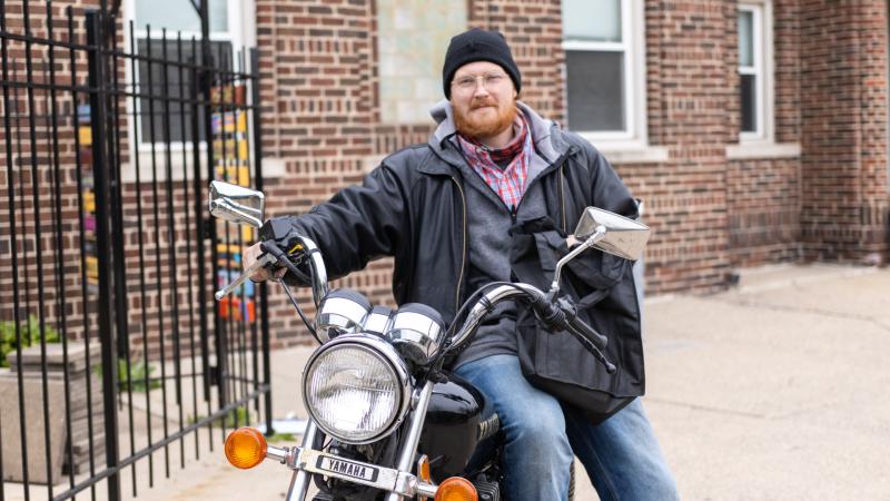 Man on motorcycle receives bag of meals