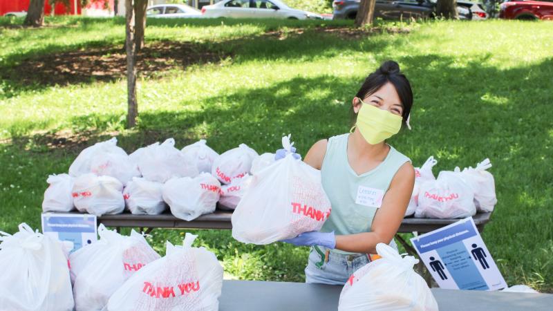 A volunteer hands out bags of food in a park