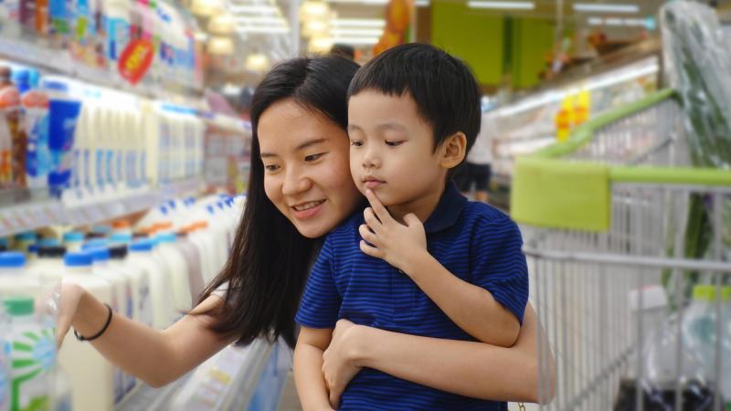 Mom and child shop for milk at grocery store