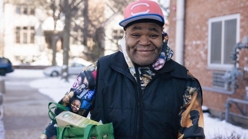 Man smiling holding a bag of groceries