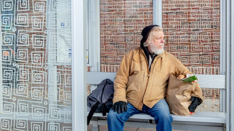 Man with groceries at a bus stop