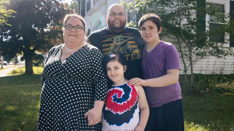 Mom, Dad, teenage son and young daughter standing together
