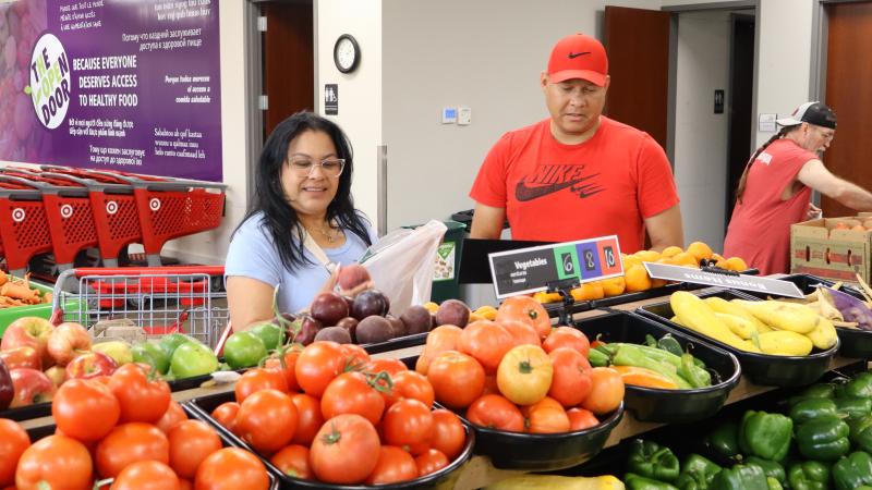 Two people pick out produce at a food shelf