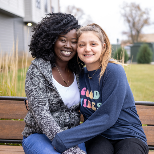 Two women sitting outside on a bench.