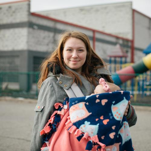 A woman with a baby smiles at the camera