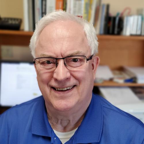 A older man smiles while sitting in office