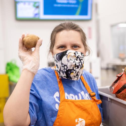 A volunteer holds a potato and smiles for the camera