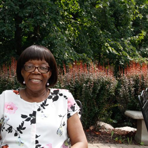 A woman smiles at the camera while sitting outside