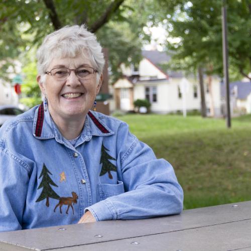Older woman sitting at picnic table smiling
