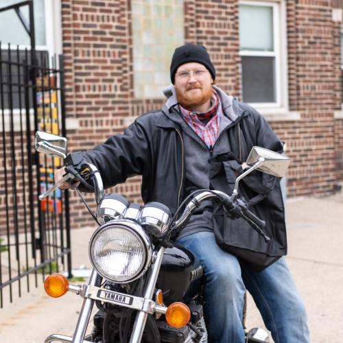 Man on motorcycle receives bag of meals