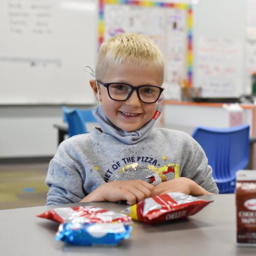 Boy with glasses eats lunch at school