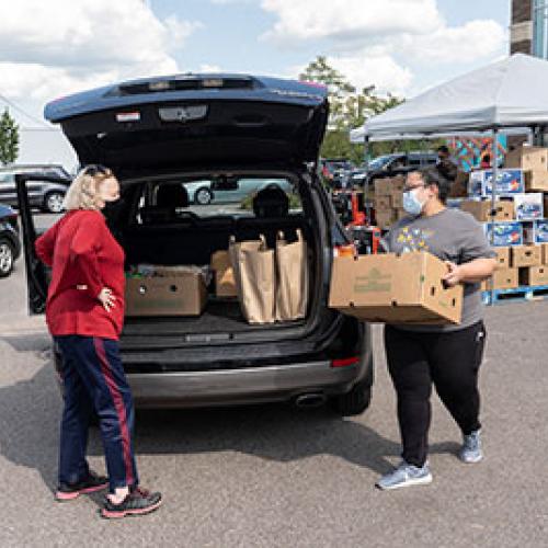 Two people load boxes into trunk during food distribution