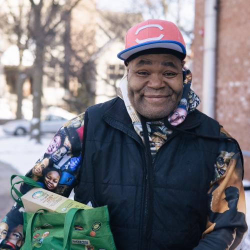 Man smiling holding a bag of groceries