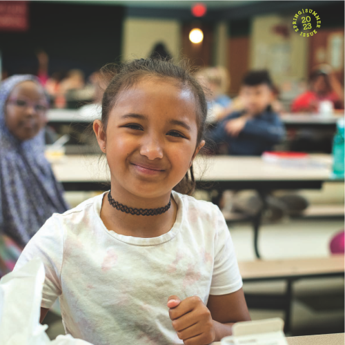 A child sitting at a lunch table with a tray of food in front of her A child sitting at a lunch table with a tray of food in front of her