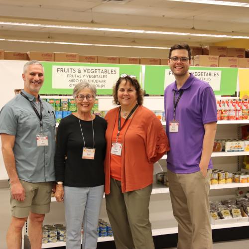 Four food bank workers stand inside a grocery store