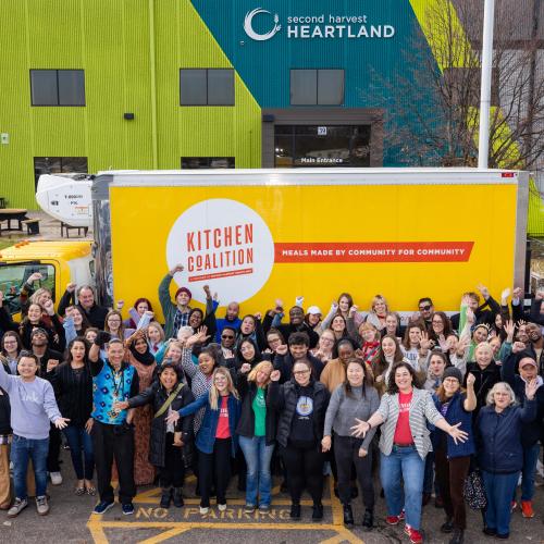 A group of people standing outside a yellow Kitchen Coalition truck at Second Harvest Heartland