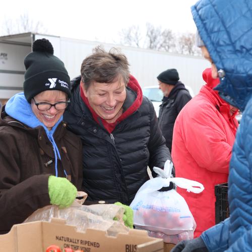 Food shelf volunteers place groceries in plastic bags outside in winter