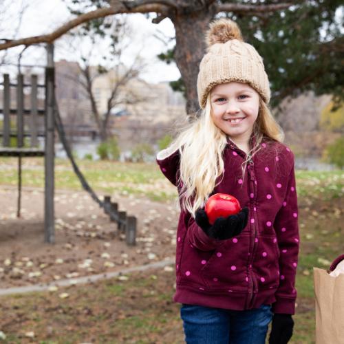 Child holding an apple while at a playground