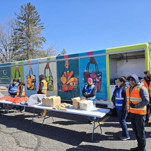 New mobile food distribution trailer A food distribution with volunteers in colorful vests in front of colorful new mobile food distribution trailer