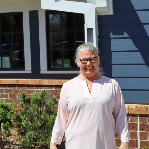 Lisa outside 360 Communities Food Shelf in Rosemount Lisa smiling in a white shirt and glasses outside 360 Communities Food Shelf in Rosemount