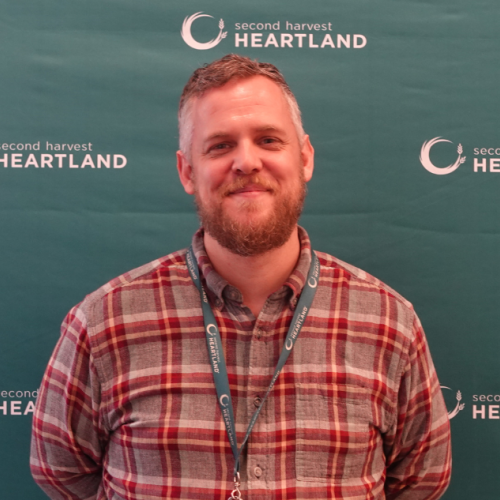 A man poses in front of a Second Harvest Heartland background