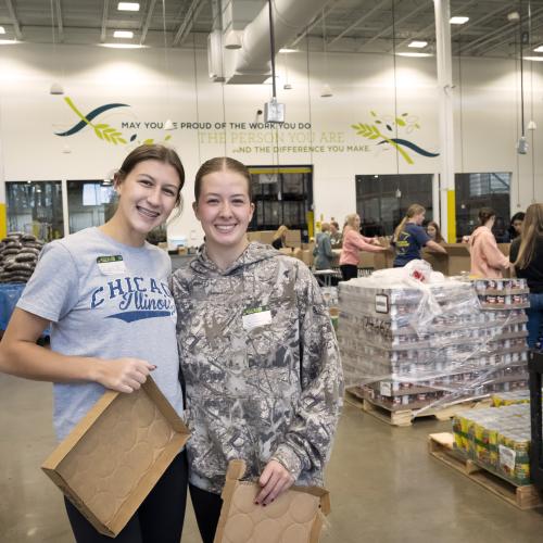 Two teenage girls posing for a picture during a volunteer food packing shift