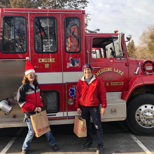 Two people pose with grocery bags outside a Medicine Lake fire truck.