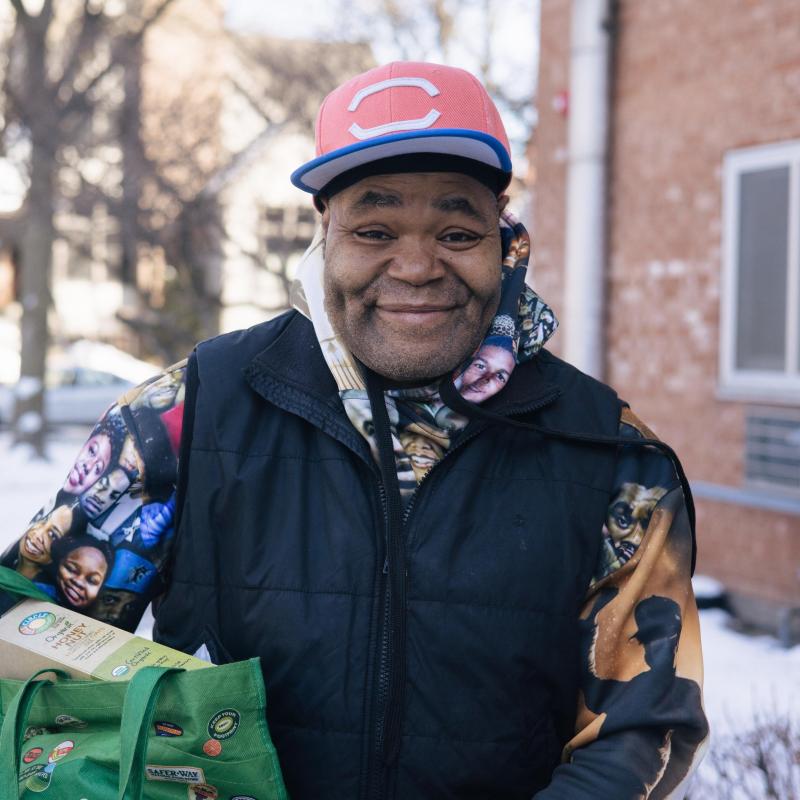 Man smiling and holding a bag full of groceries