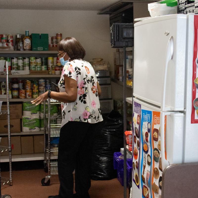 A woman puts food on a shelf 