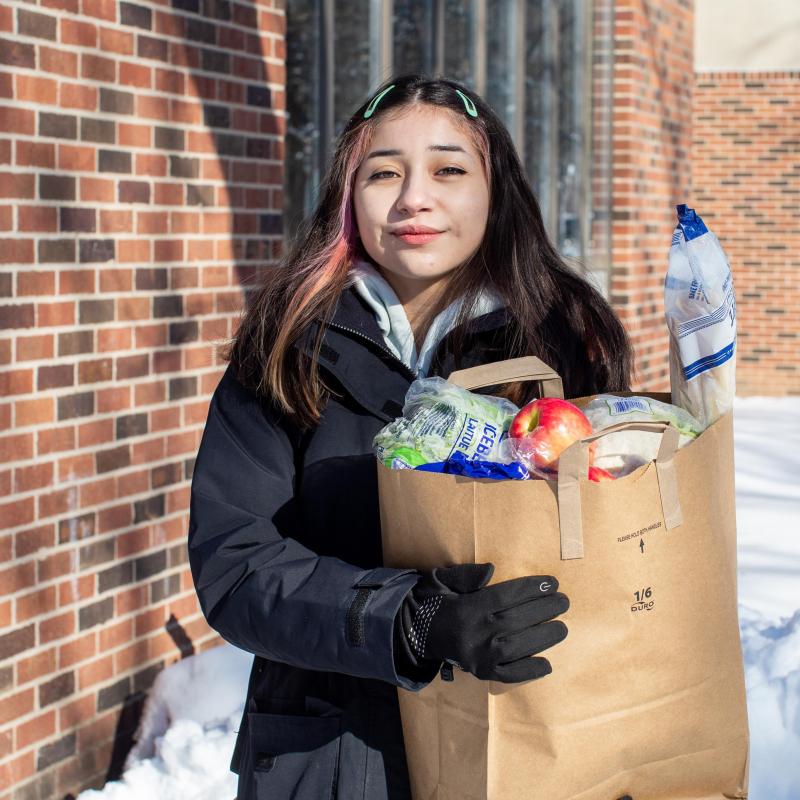 Young woman holds grocery bag outside in winter