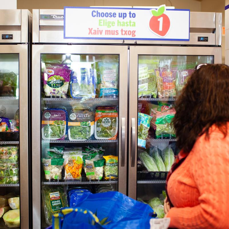 A woman stands in front of a cooler of food. Credit to: Ryan Stoppera FreeTruth Media