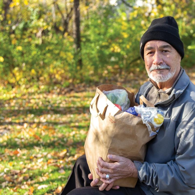 Man with grocery bag outside with hat on
