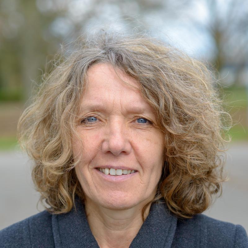 A woman stands outside and looks at the camera