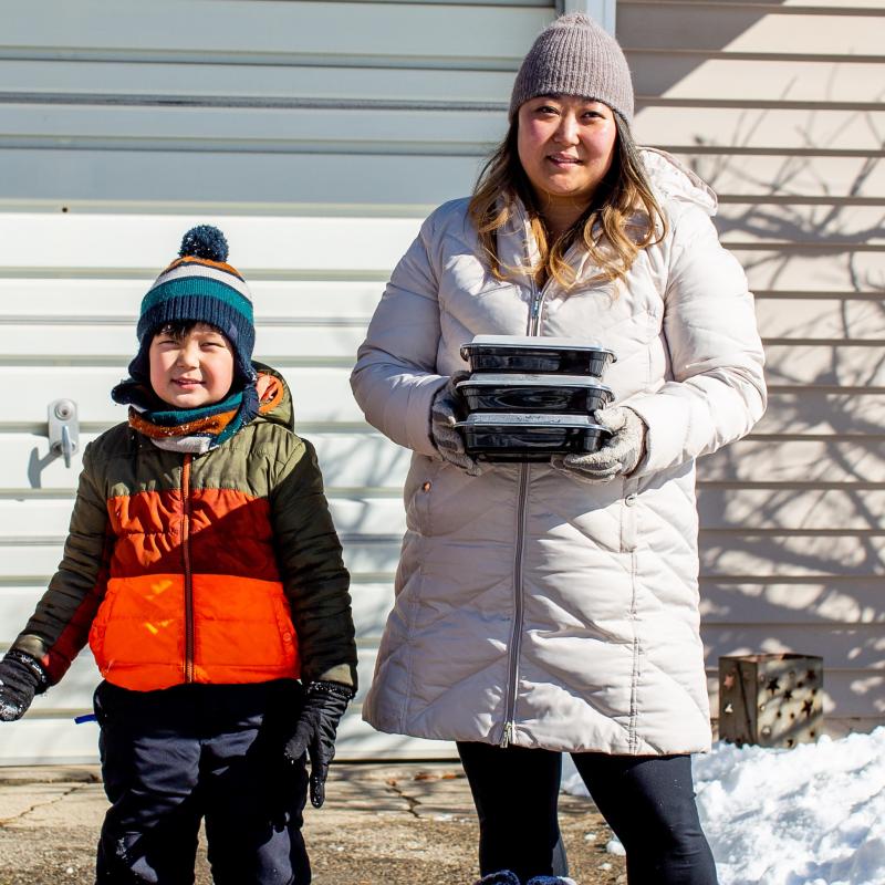 Mom and kid with boxed meals in winter