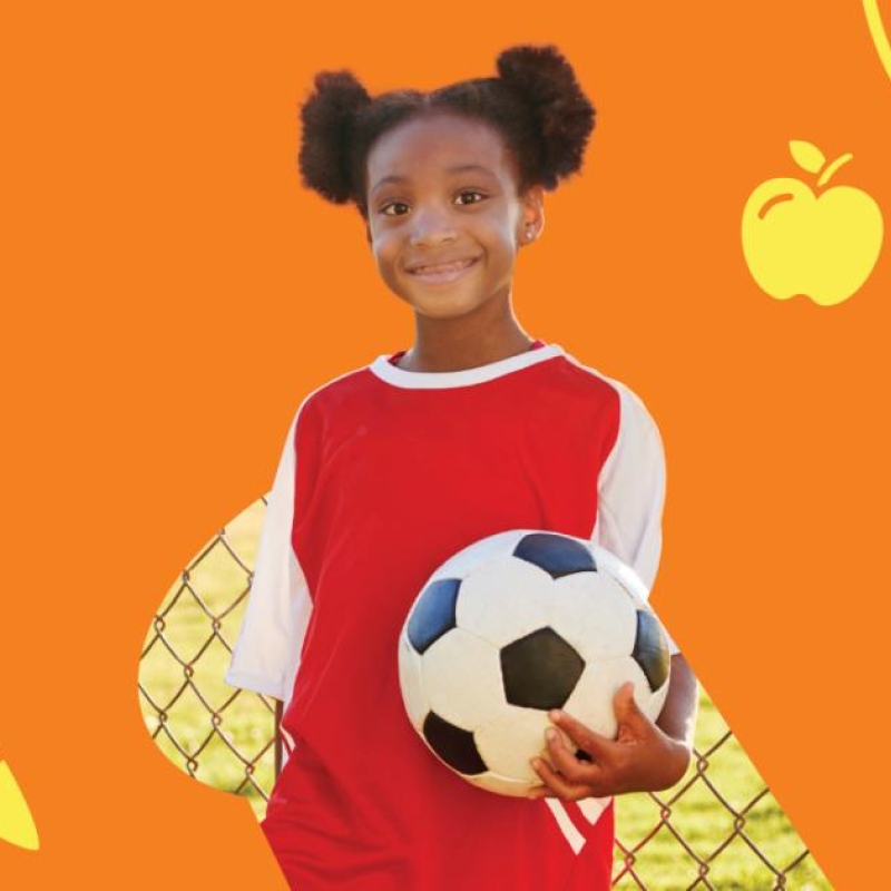 A little girl holding a soccer ball in front of an orange back-drop