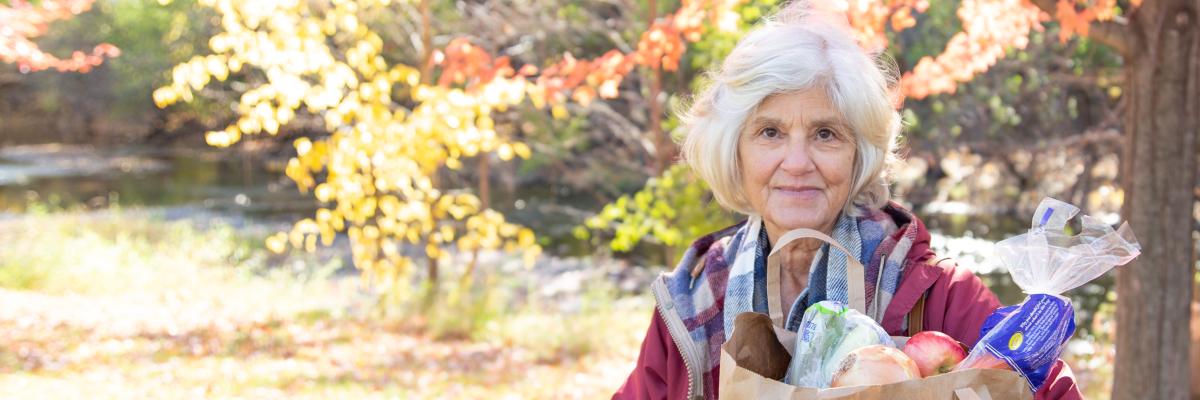 Old woman holding bag of groceries