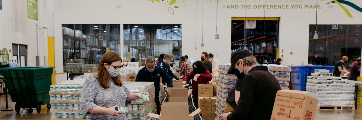 A dozen volunteers place food in boxes along an assembly line