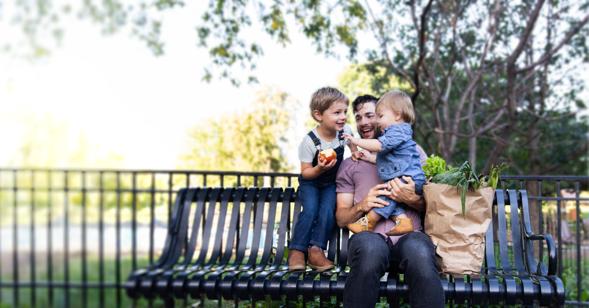 A father sitting on a bench outdoors with his two children