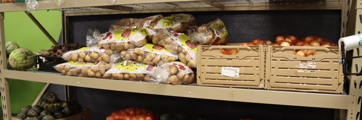 Potatoes, onions and summer squash on the shelves of a food shelf