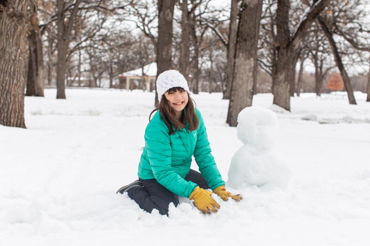 Child in snow playing making snowman