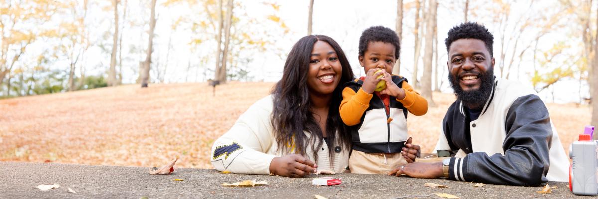two adults and toddler sitting at outdoor table