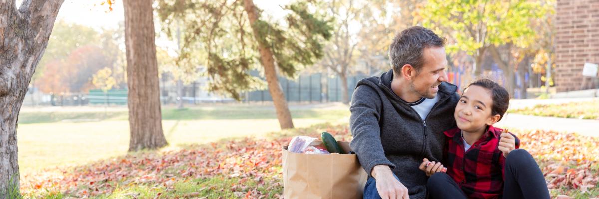 Father and daughter eat outside on a fall day